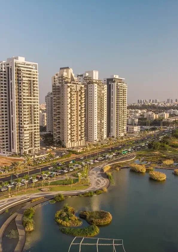 צילום: בנייני מגורים גבוהים באור של שעת ערב, מול שמיים בהירים, ובמרחק שכונות העיר