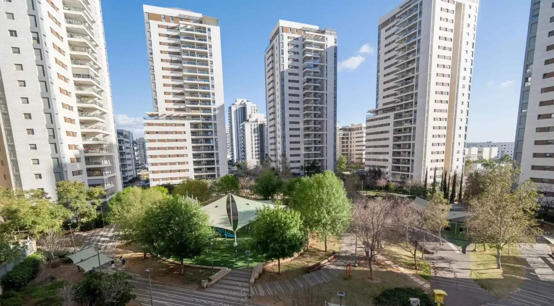 נוף מהחלון אל חצר משותפת, פארק ומגדלי מגורים
