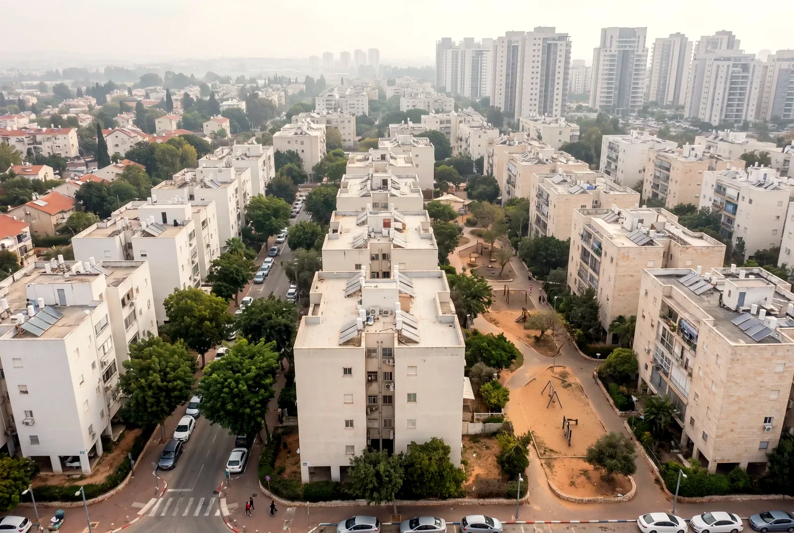 הדמיה: מבט מרחפן באלכסון על שכונת מגורים עם בנייני דירות, פארק קטן ומגדלים ברקע.