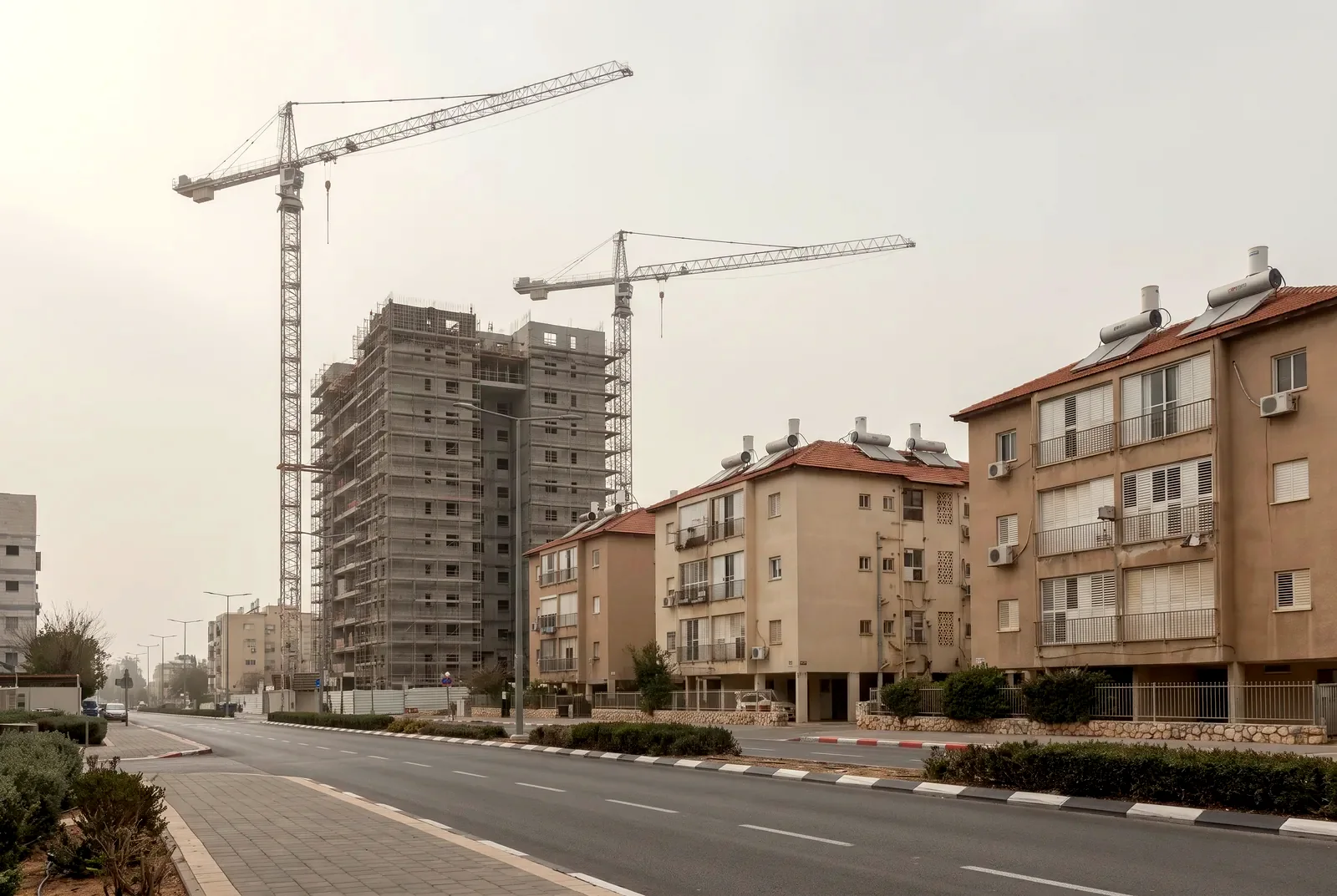 הדמיה: אתר התחדשות עירונית עם שני עגורני צריח ומגדל מגורים בבנייה, לצד בנייני דירות ותיקים ומטופחים.