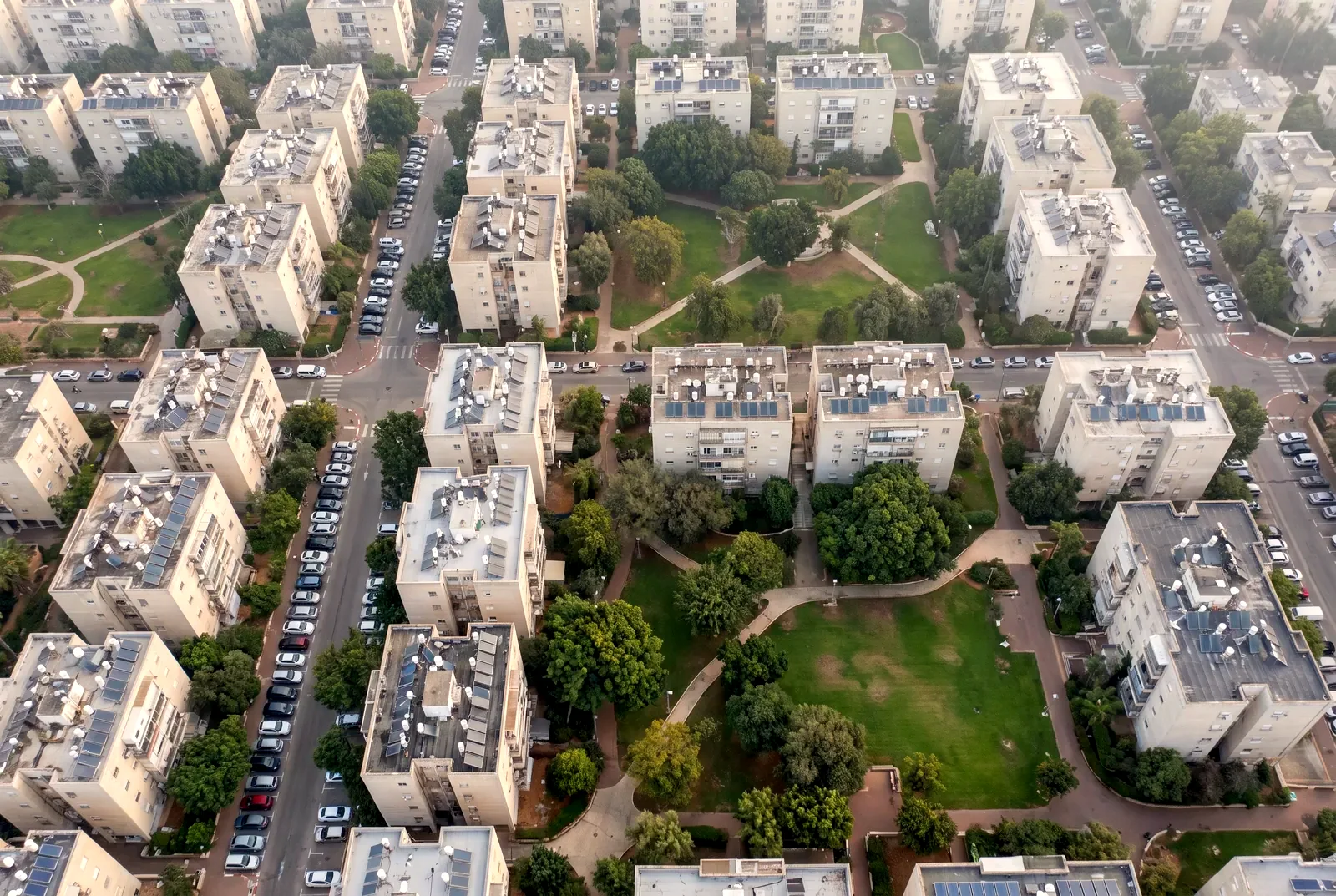 הדמיה: מבט ישר מלמעלה על שכונת מגורים עם בנייני דירות, רחובות עם עצים וחניות, וגן שכונתי ירוק באמצע.