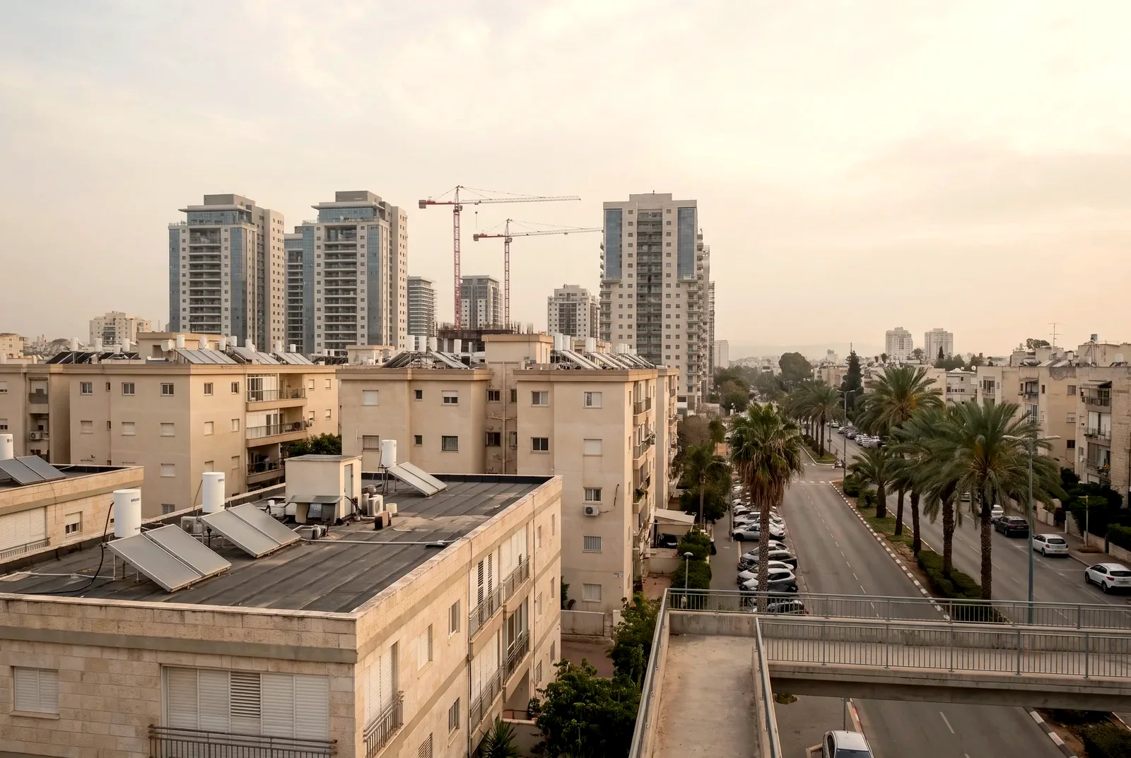 הדמיה: מבט מגשר על גגות בנייני מגורים ותיקים ומאחוריהם מגדלים חדשים ומנופים