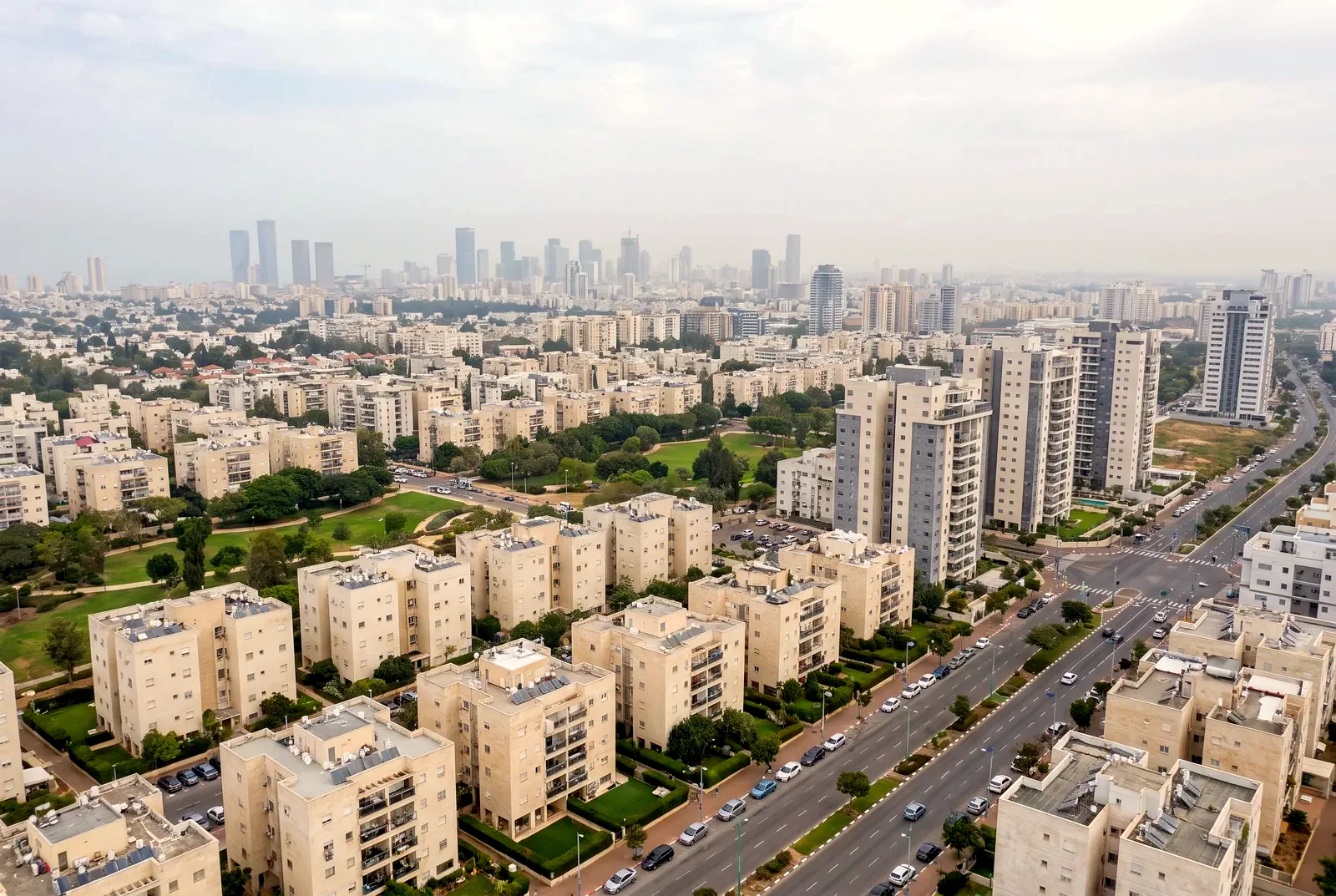 הדמיה: פנורמה מהאוויר על עיר עם שכונות מגורים, פארקים ומגדלים באופק
