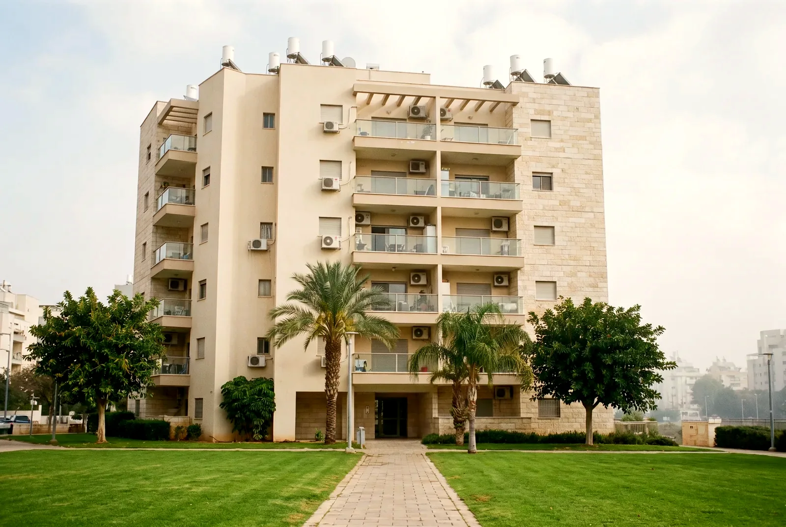 הדמיה: חזית של בניין מגורים בן שמונה קומות מעבר למדשאה מסודרת, עם מרפסות ודקלים