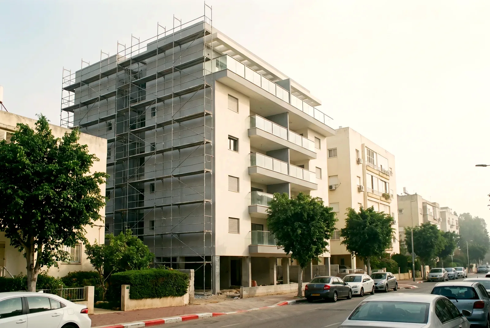 הדמיה: רחוב מגורים ובו בניין ותיק עם קומה חדשה בחיפוי אבן ופיגומים פשוטים בצד