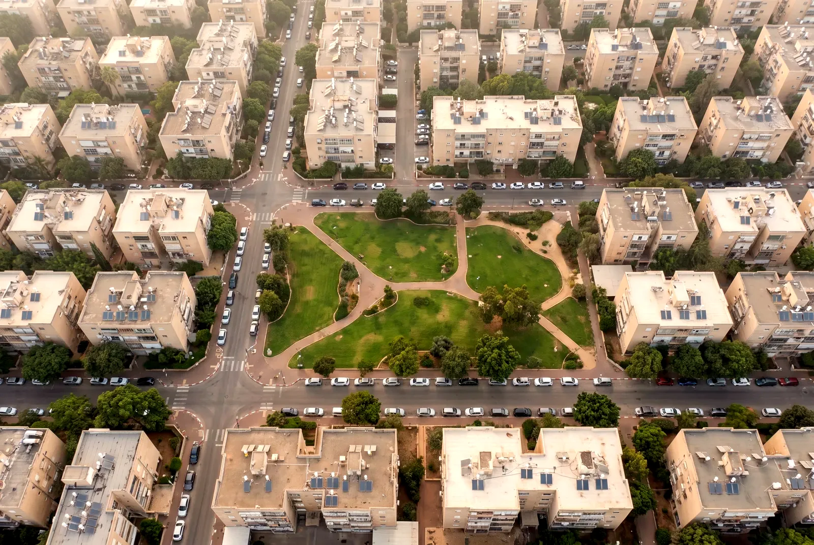 הדמיה: מבט אווירי ישר מלמעלה על בנייני דירות, רחובות ופארק ירוק בשכונת מגורים