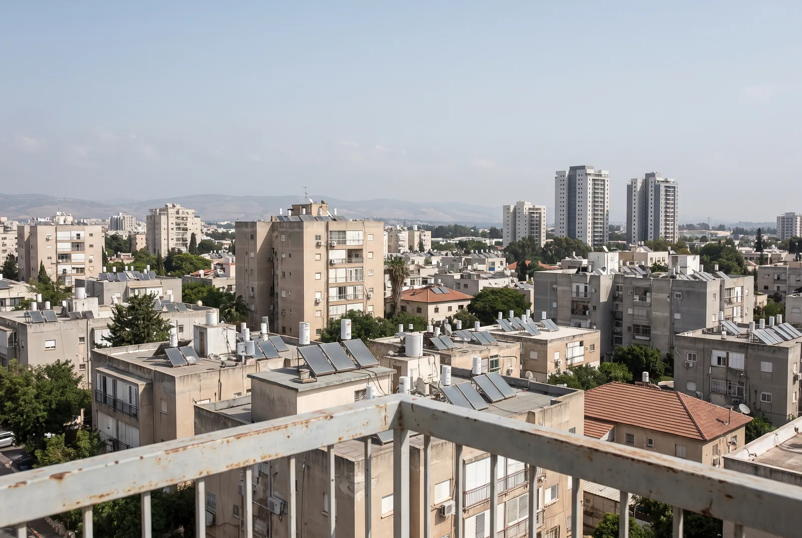 הדמיה: נוף עירוני ממרפסת גבוהה, גגות, בנייני מגורים ומגדלים באופק