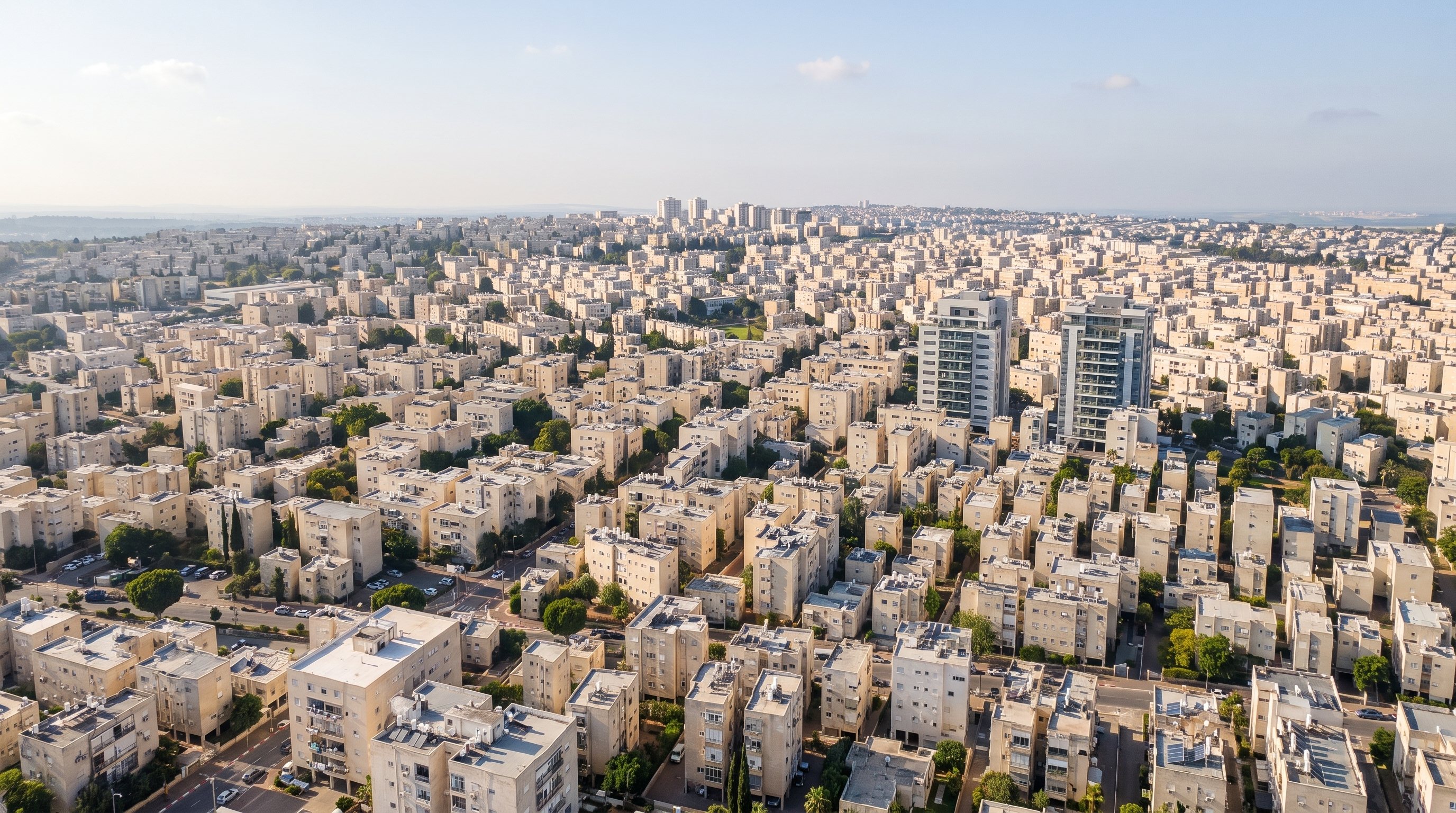 הדמיה: מבט מגובה על שכונות מגורים בפתח תקווה ביום בהיר, בנייני מגורים בצבעי חול ושני מגדלים
