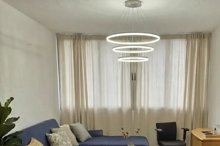 סלון בדירה בשפרינצק בפתח תקווה: ספה כחולה, וילונות ונברשת עגולה